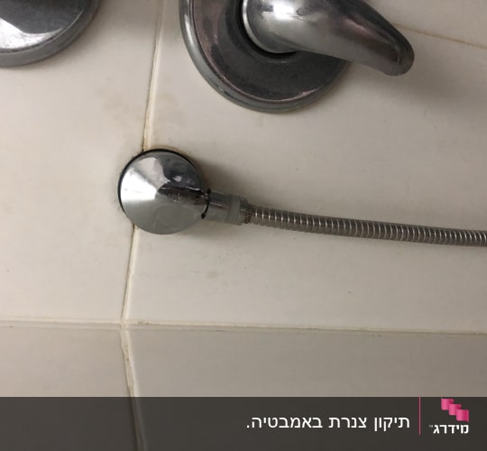 ברז מתכת עם צינור גמיש מחובר לקיר